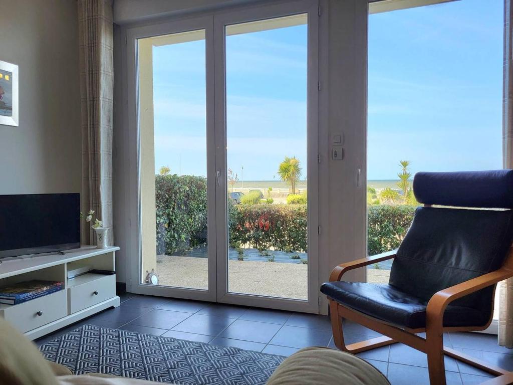 - un salon avec une chaise et une porte coulissante en verre dans l'établissement Appartement rez-de-jardin, front de mer, 4 pers, calme, wifi gratuit - FR-1-465-46, à Merville-Franceville-Plage