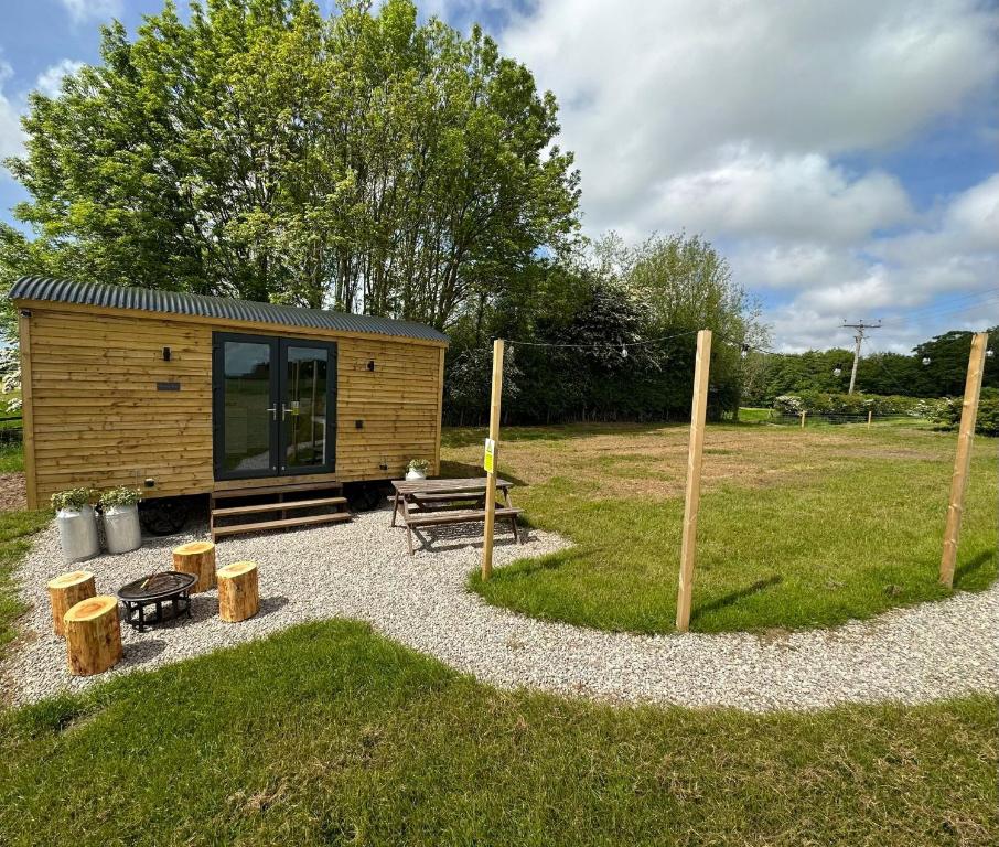 a small cabin with a bench and a picnic table at The Stag's Head - Shepherds Hut in Great Singleton