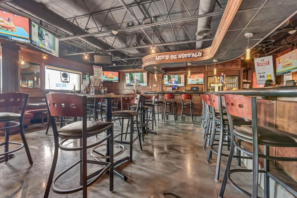 Un bar con sillas y mesas en un restaurante. en Buffalo Airport Hotel, en Cheektowaga