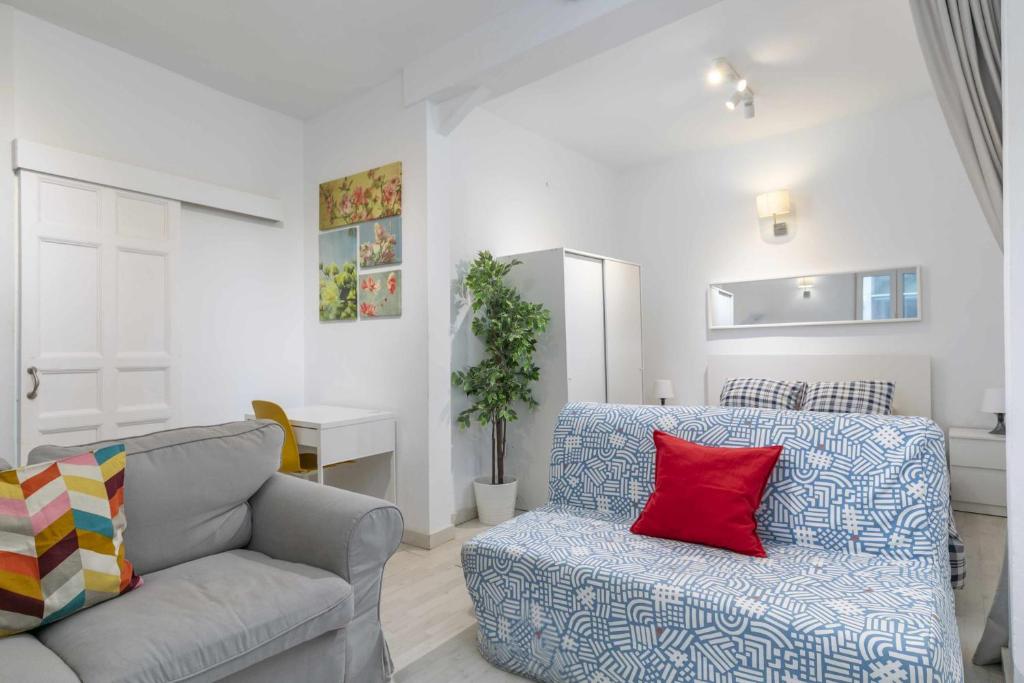 uma sala de estar com um sofá e uma almofada vermelha em Apartamento céntrico y confortable em Madri