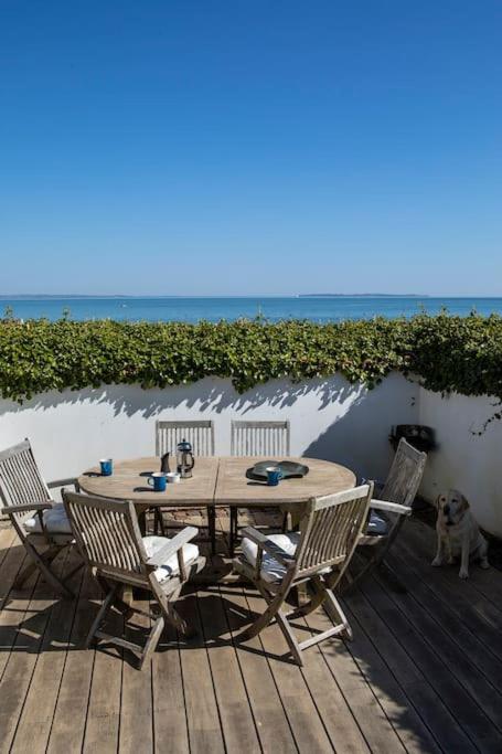 a wooden table and chairs on a deck with a dog at Historical beachhouse in Snekkersten in Snekkersten
