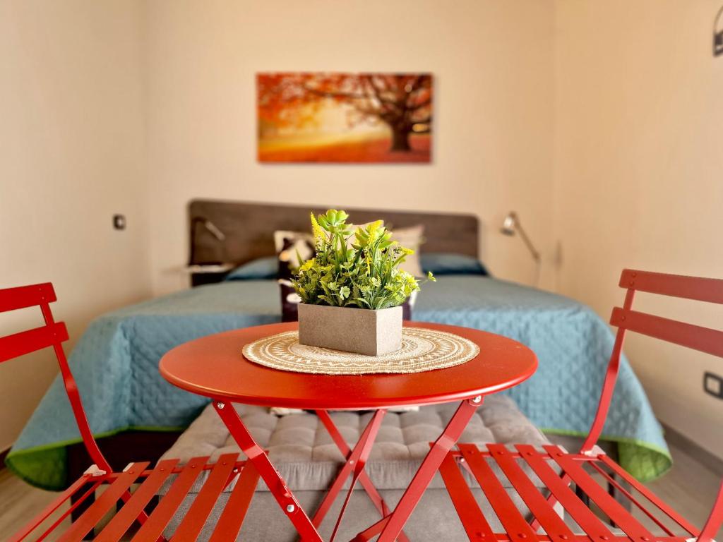 a red table with a plant on it in a room at La finestra sul cortile by TraMonti Apartments in LʼAquila