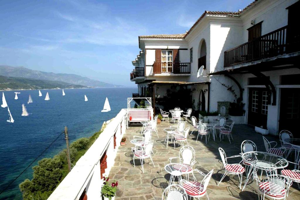 eine Terrasse mit Tischen, Stühlen und Wasser in der Unterkunft Mirini Hotel in Samos