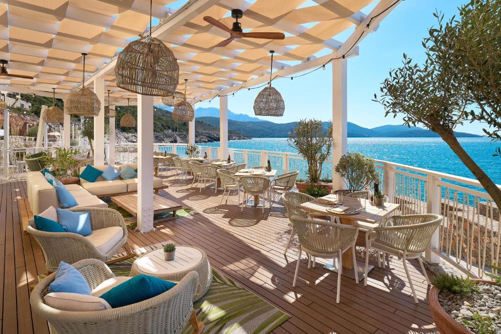 a patio with tables and chairs and a view of the water at The Chedi Luštica Bay in Tivat