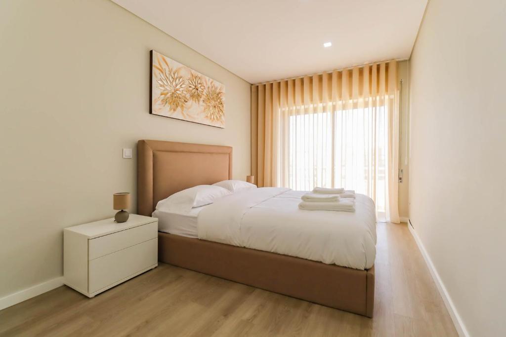 um quarto com uma cama grande e uma janela em Sunshine Apartment - Modern Ap Near the Beach em Viana do Castelo