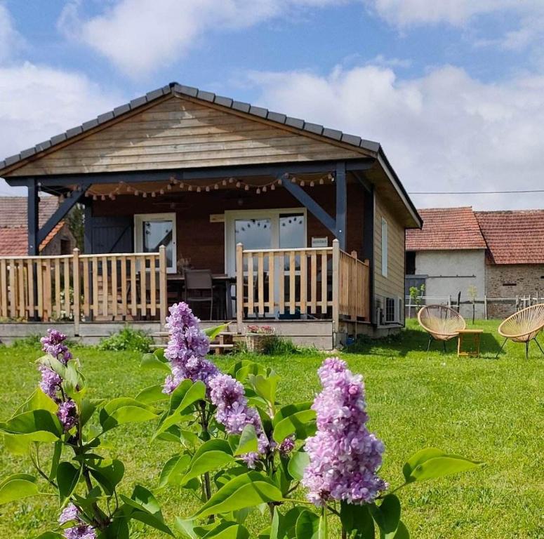 ein Haus mit einer Veranda mit lila Blumen im Hof in der Unterkunft Gîte, aux portes du Morvan in Voudenay-lʼEglise