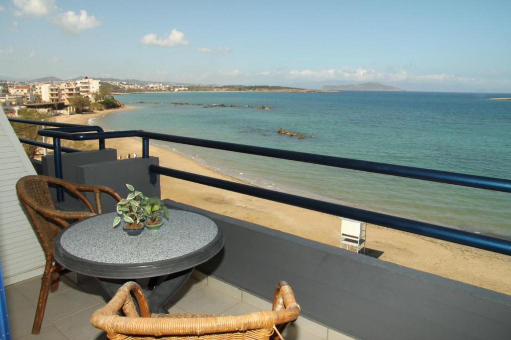 een tafel en stoelen op een balkon met uitzicht op de oceaan bij Danaos Hotel in Chania