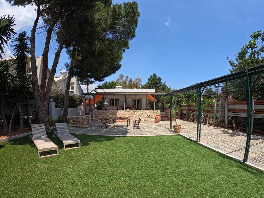 a yard with chairs and a patio with a house at Hector Villa Airport by Airstay in Artemida