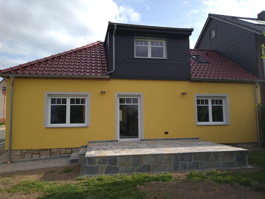 uma casa amarela com um telhado preto em Ferienhaus Opolka em Balgstädt