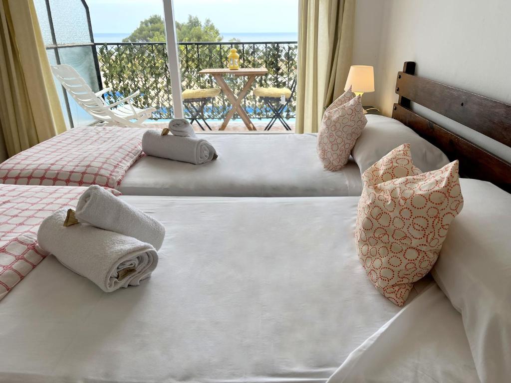1 dormitorio con 2 camas, toallas y balcón en Studios LES TERRASSES de Cala Llevado en Tossa de Mar