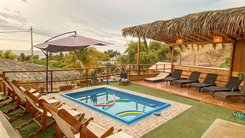 uma piscina com cadeiras e um guarda-sol em Terrazas Iguana em Máncora