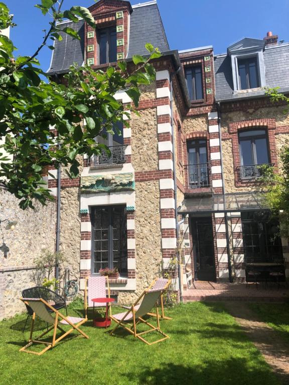ein altes Haus mit Stühlen im Hof in der Unterkunft Villa Centre ville et plage Le Mascaret in Villers-sur-Mer