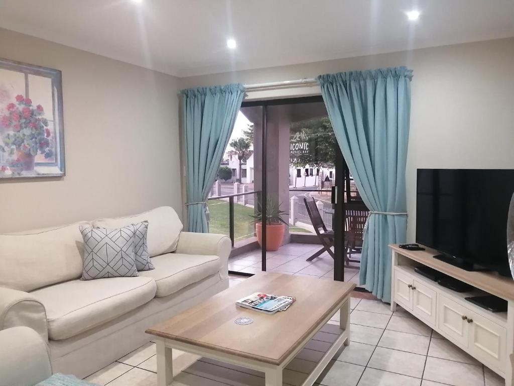 a living room with a couch and a tv at 2-Bedroom Apartment within 1km of The Point Beach in Mossel Bay