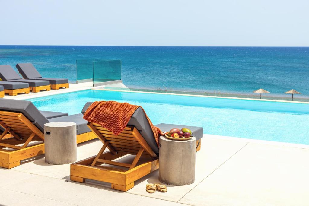 a swimming pool with two chairs and a bowl of fruit at Villa Seven in Lachania