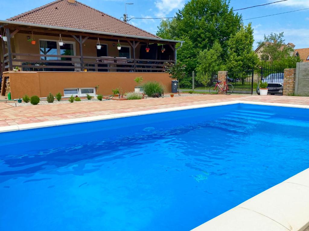 a blue swimming pool in front of a house at Vivien vendégház 1 in Ordacsehi
