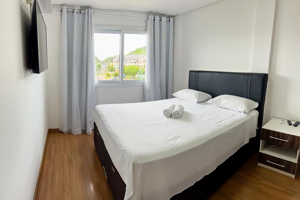 a bedroom with a large white bed with a window at apartamento em gramado in Gramado