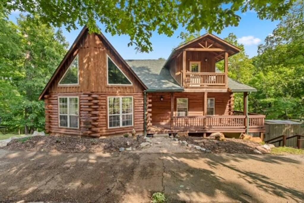 Casa de madera con porche y balcón en Main Lodge at Lake Forest Cabins en Eureka Springs