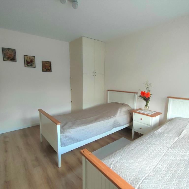 ein Schlafzimmer mit 2 Betten und einem Tisch mit Blumen darauf in der Unterkunft Kurka Wodna - Apartamenty na Mazurach in Dłużek