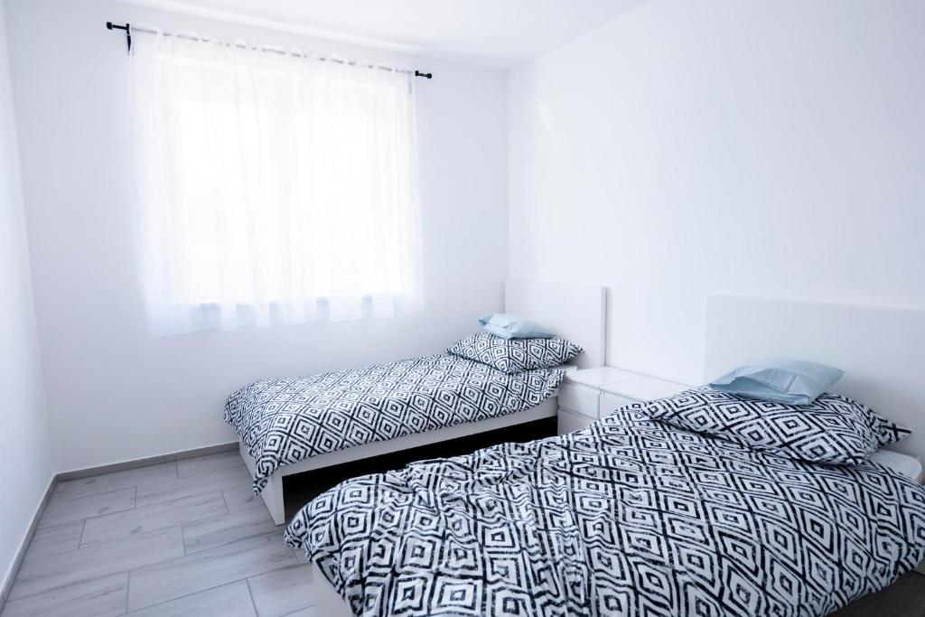 1 dormitorio con 2 camas individuales y ventana en Vivien vendégház 2, en Ordacsehi