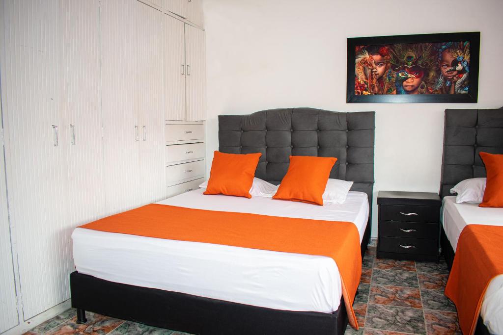 a bedroom with two beds with orange pillows at Hotel BogoSuba 127 in Bogotá