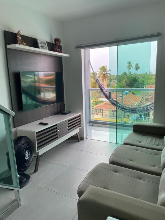 sala de estar con TV de pantalla plana y sofá en Maragogi , Peroba Ville Apartamento com piscina, en Maragogi