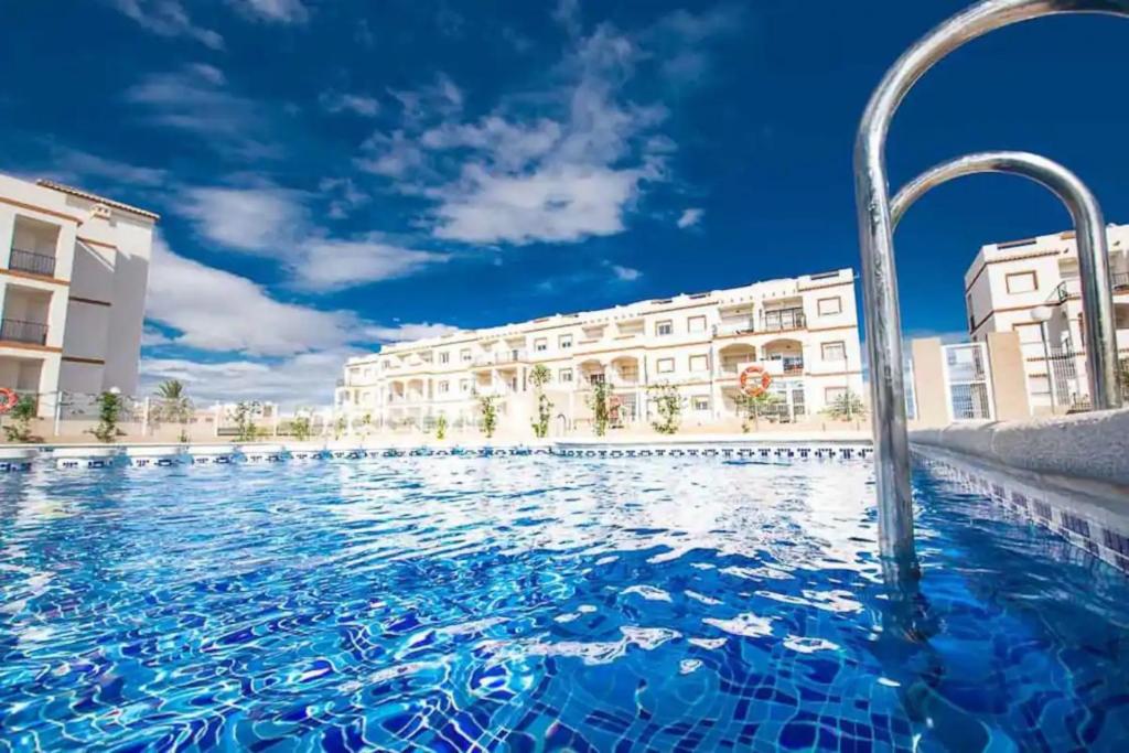 a swimming pool with blue water in front of buildings at Casa Flamingo Private Residence in Orihuela