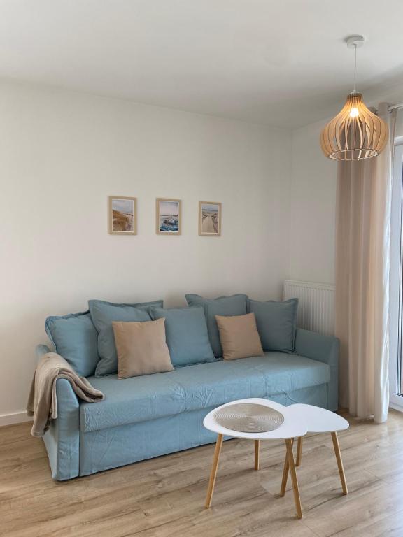 un divano blu in un soggiorno con un tavolo di Apartamenty Ustronie Morskie31B4 a Ustronie Morskie