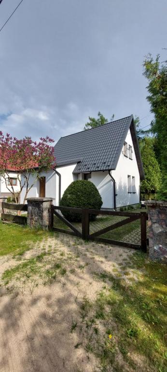 a white house with a fence in front of it at Domek Letniskowy na Mazurach in Giżycko