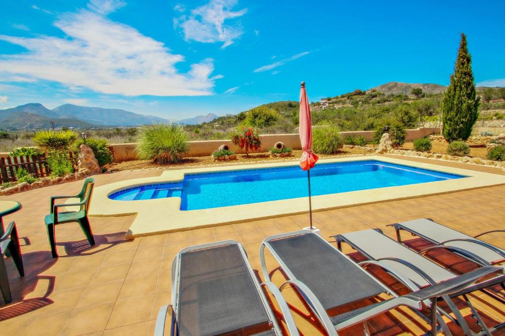 una piscina con sillas y sombrilla en Quicano - magnificent views and private pool in Lliber, en Lliber