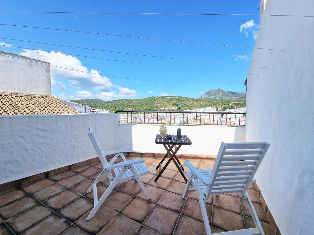 eine Terrasse mit 2 Stühlen und einem Tisch auf dem Balkon in der Unterkunft EL BÚCARO. Las Puertitas Rojas in Ubrique