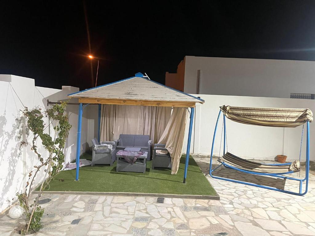 einen Pavillon mit einem Stuhl und einer Hängematte in der Unterkunft Holiday home by the sea, Gabes in Tacape