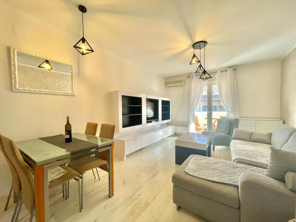 a living room with a table and a living room with a couch at Family One bedroom apartment with Garden view in Budva