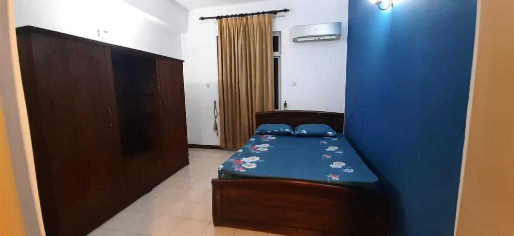 a bedroom with a bed and a blue wall at Rudra Residence Apartment in Colombo