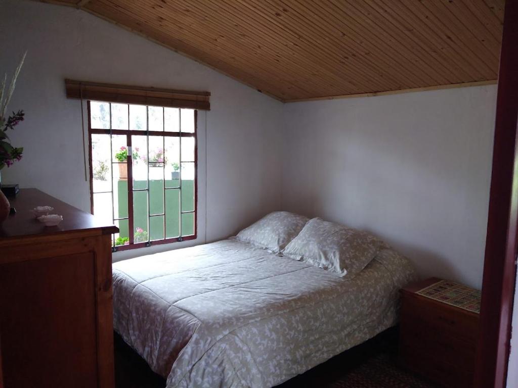 a bedroom with a bed and a window at La Reliquia - Tausa in Barranquilla