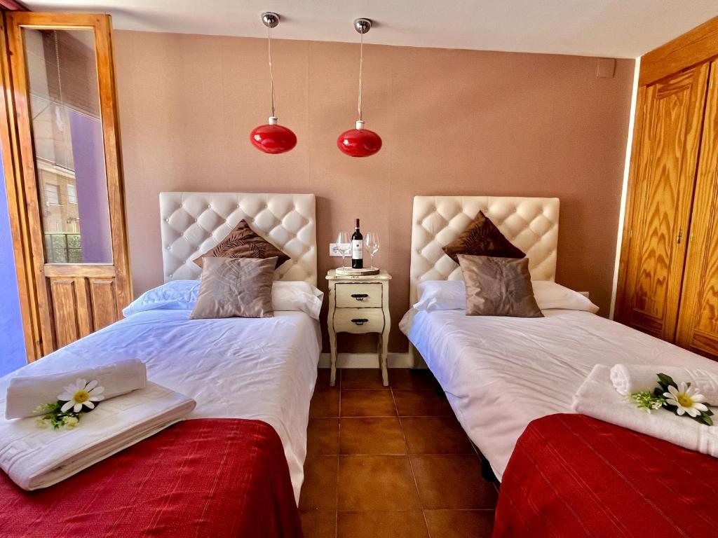 1 dormitorio con 2 camas con sábanas blancas y flores en Hostal - Restaurante Nomadas by Gloove, en Villalba de la Sierra