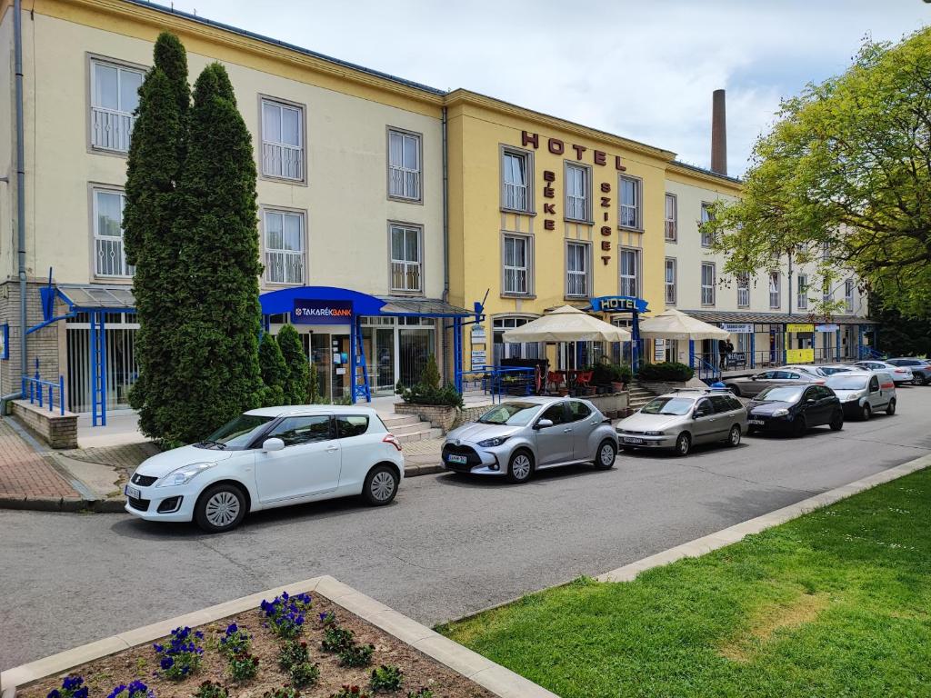 una fila de autos estacionados frente a un edificio en Hotel Béke Sziget Komló, en Komló