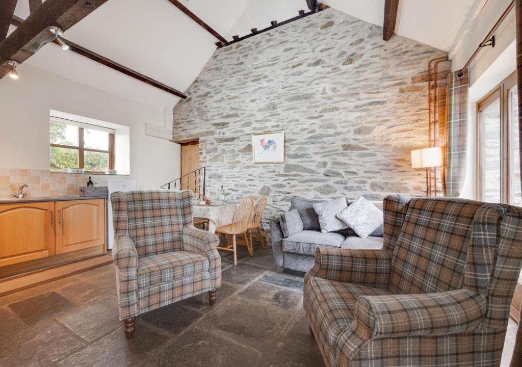 a living room with two chairs and a stone wall at Cysgod-y-coed in Builth Wells