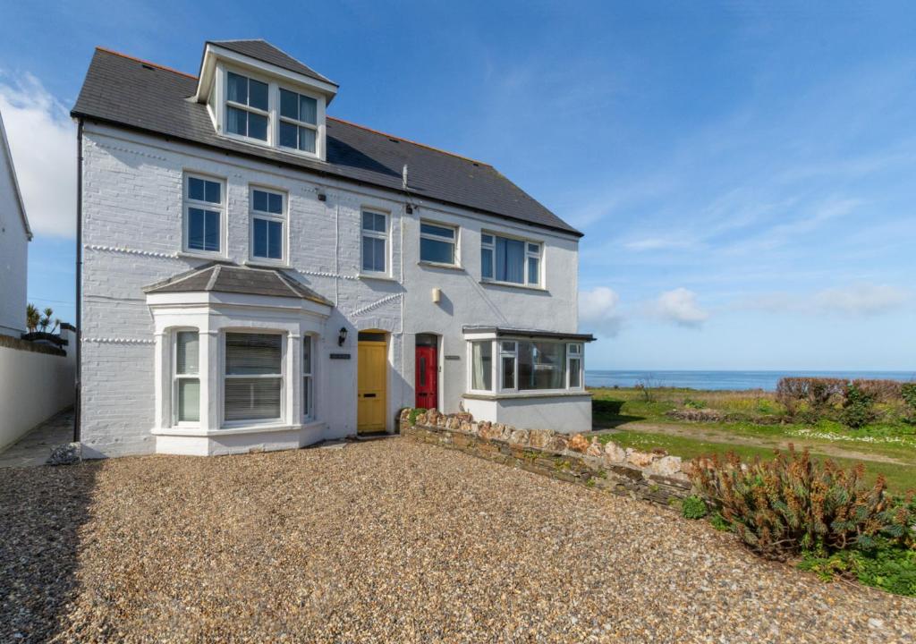 a white house with a red door and the ocean at Chy An Porth in Padstow