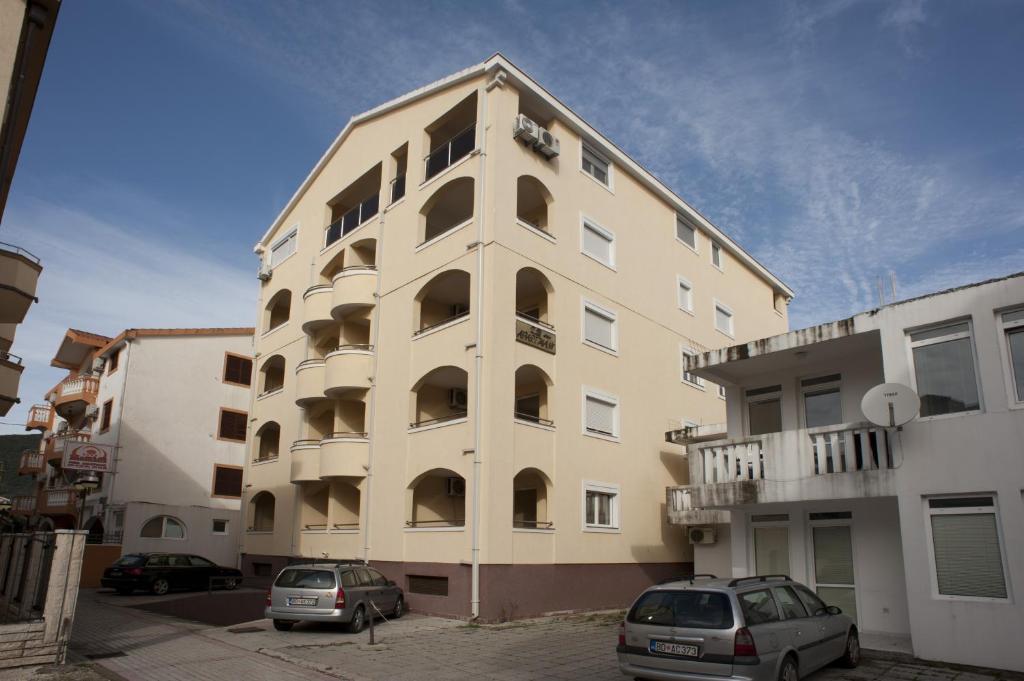 a tall building with cars parked in front of it at Apartmani Jovan in Budva