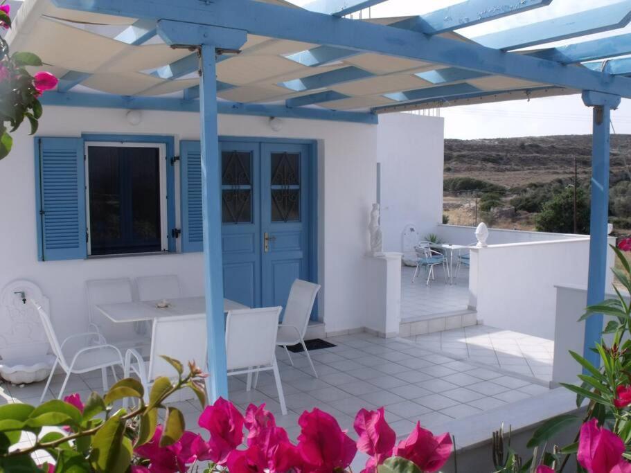 a patio with a table and chairs and pink flowers at Milithos Apartments 1 in Adamantas