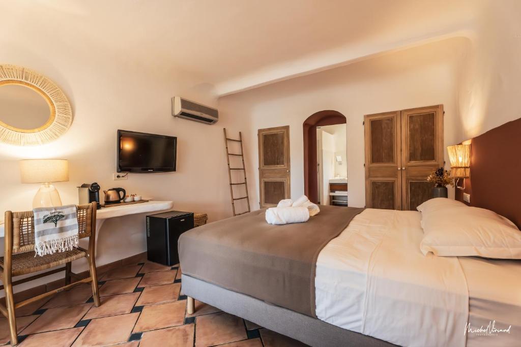 a bedroom with a bed and a desk and a mirror at Hôtel Palombaggia in Porto-Vecchio
