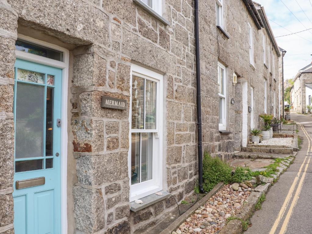 a stone house with a blue door on a street at Mermaid Cottage in Penzance