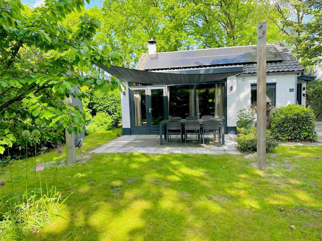 een huis met een tafel en stoelen in een tuin bij Natuurhuisje Bergvliet - Nature, Golf & Wellness in Oosterhout