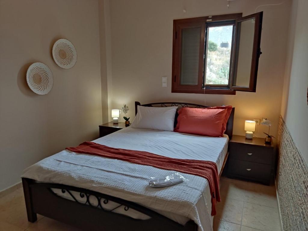 Un dormitorio con una cama con almohadas rojas y una ventana en Mani spot in Yerolimin, en Yerolimin