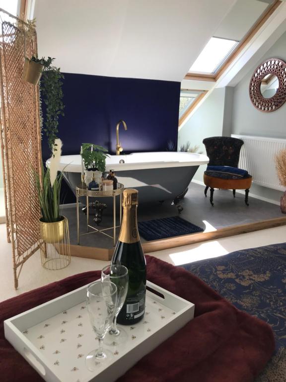 a bottle of champagne and two glasses on a table in a bathroom at Willow Barn luxury countryside accommodation in Bury St Edmunds in Bury Saint Edmunds