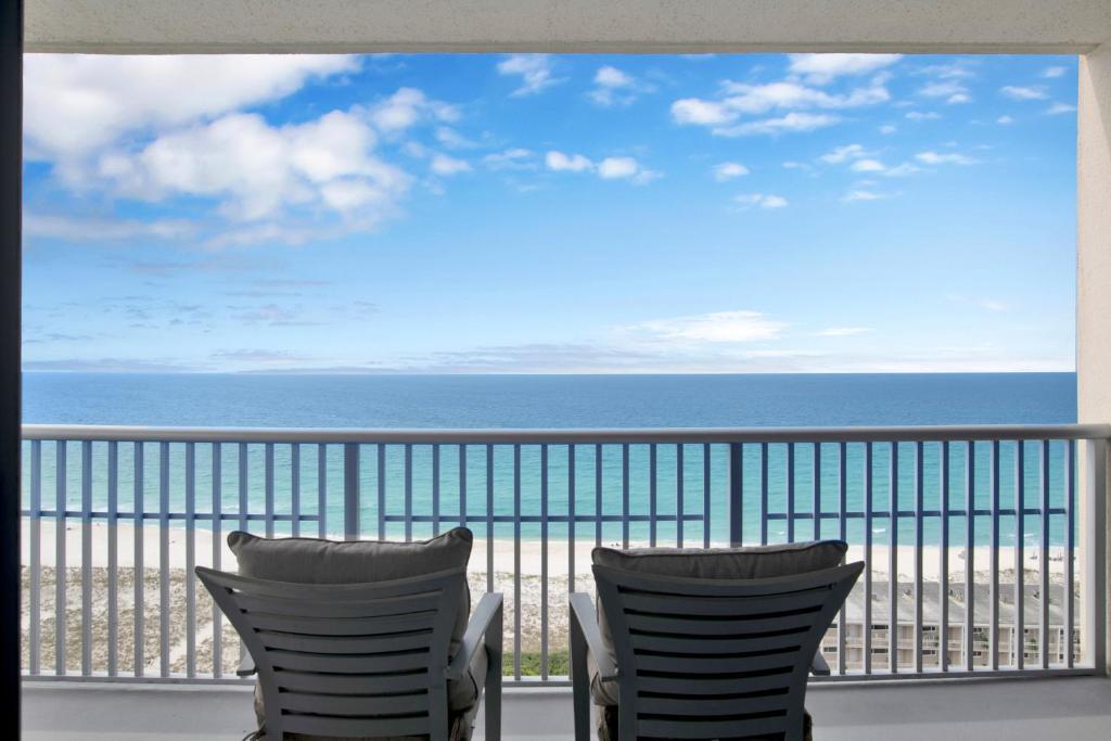 a view of the beach from a balcony with chairs at Emerald Dolphin #1610 in Pensacola Beach