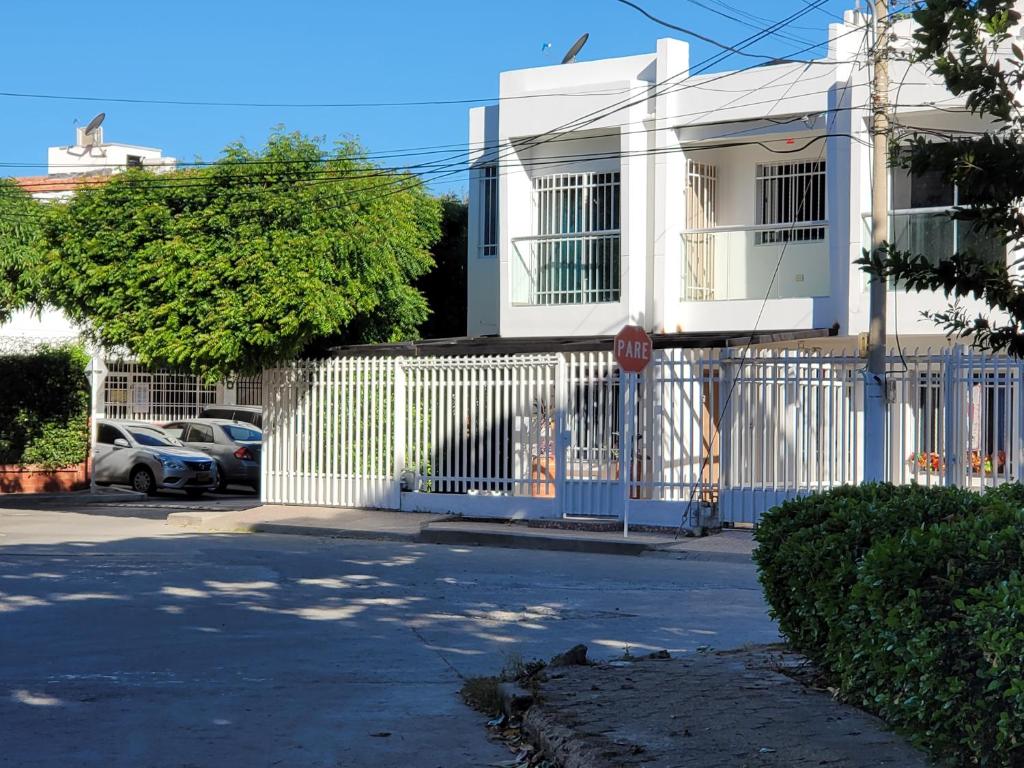een wit huis met een poort en een stopbord bij Prefect get away in Santa Marta