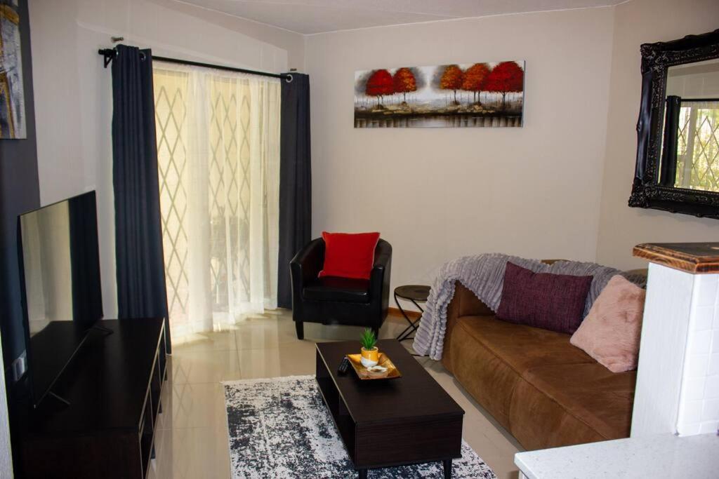 uma sala de estar com um sofá e uma cadeira em A homely and secure 2 bedroom with uncapped Wifi em Joanesburgo