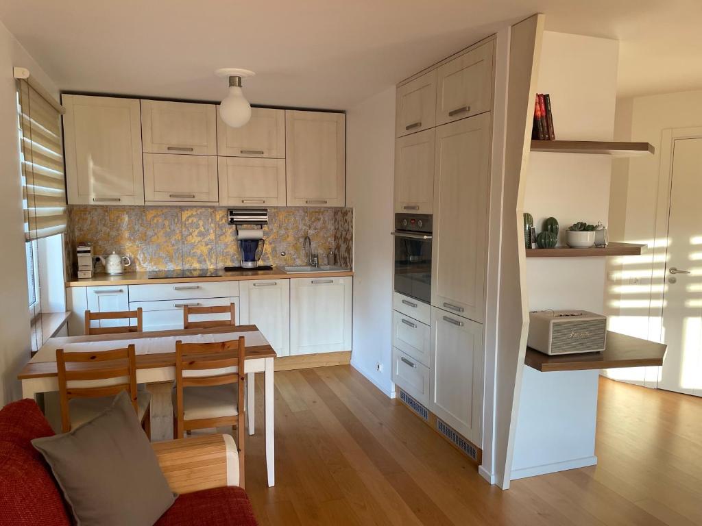 a kitchen with white cabinets and a table with chairs at Happy Viesturs in Valmiera