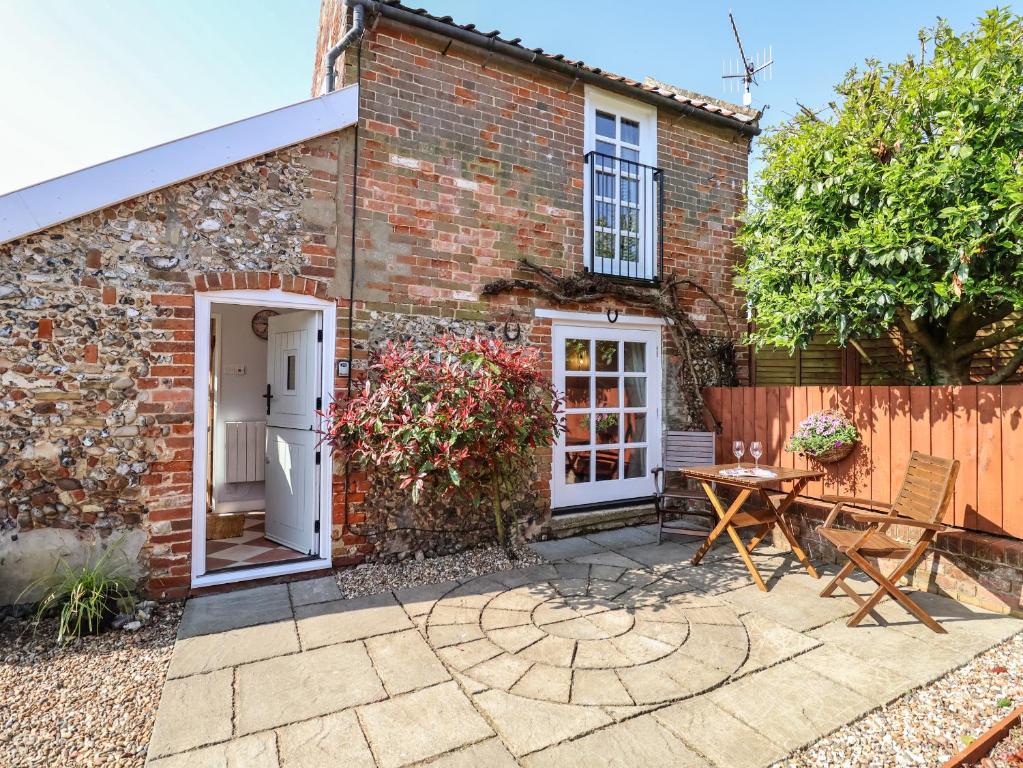 a brick house with a patio and a table at Admiral Cottage in Woodbridge